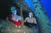 Zwei Unterwassermodels posieren mit venezianischen Masken im Steuerstand der Ghiannis D. (Ägypten, Rotes Meer), underwater models  at the shipwreck of Ghiannis D. (Aegypt, Red Sea)