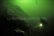 Taucher erkundet Felswand im Zugersee (Schweiz)